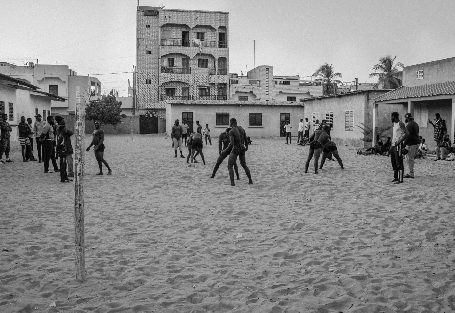 The wrestling school's sand yard at dusk with a few pairs training