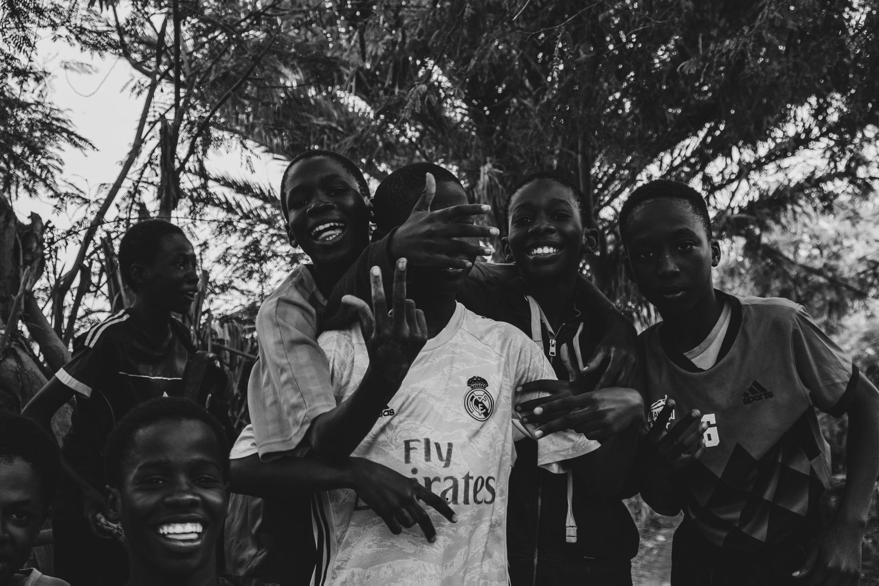 A group of boys laughing and posing under trees